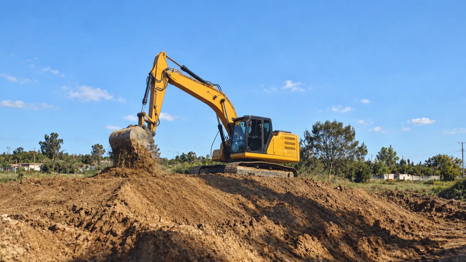 Retroexcavadora esparciendo relleno en un terreno
