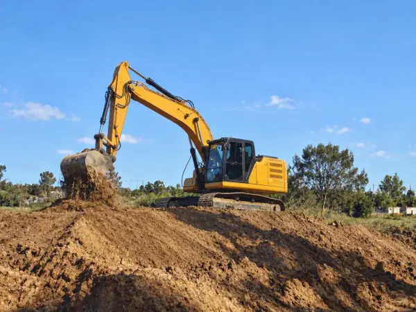 Retroexcavadora esparciendo relleno en un terreno